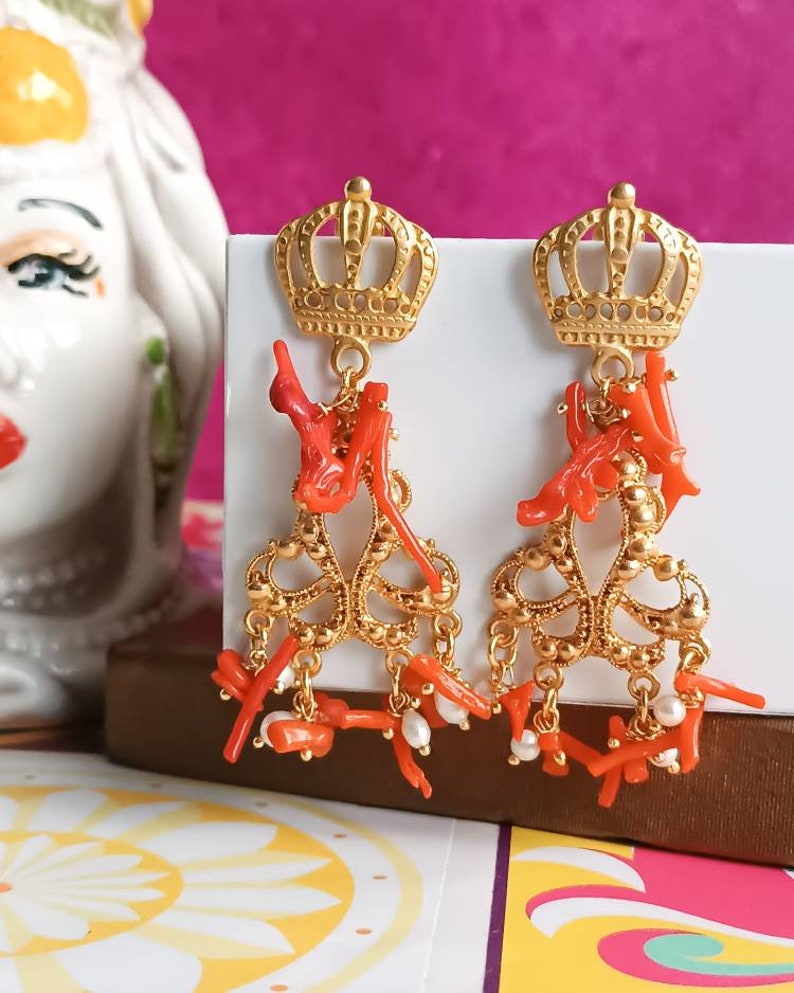 May include: Gold crown earrings with dangling coral and pearl accents.