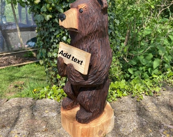 Chainsaw carved bear holding sign
