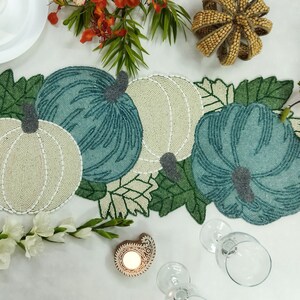 Puede incluir: Un camino de mesa de cuentas con un diseño de calabazas verdes y blancas y hojas. El camino de mesa es perfecto para una mesa de otoño o de Acción de Gracias.