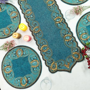 Può includere: Un set di tovagliette all'americana in perle blu turchese con accenti dorati e marroni. Le tovagliette presentano un motivo paisley e sono perfette per aggiungere un tocco di eleganza a qualsiasi tavolo da pranzo.