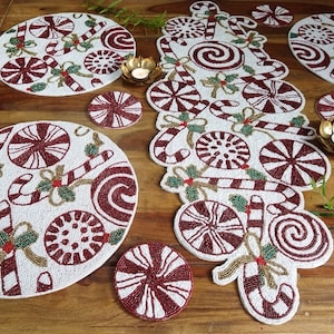 Puede incluir: Un juego de manteles individuales de cuentas blancas con un diseño de bastón de caramelo y menta roja y blanca. El juego incluye un camino de mesa, cuatro manteles individuales y cuatro posavasos.