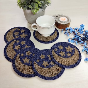 May include: Set of six blue and gold beaded coasters featuring a crescent moon and stars design.