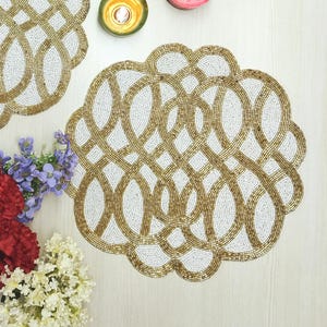 Mantel individual de cuentas hecho a mano en blanco roto y dorado. Disponible en juegos de 2, 4 y 6.
