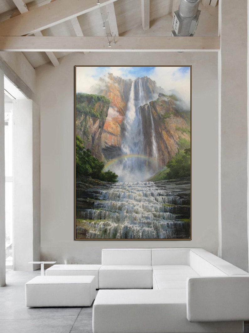 May include: A painting of a waterfall cascading down a rocky cliff face. Lush green foliage surrounds the base of the waterfall, and a rainbow arches over the water. The painting is framed in a brown wood frame.