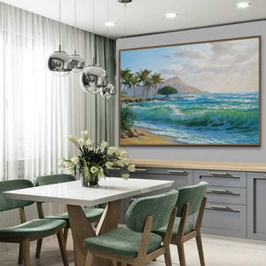 Puede incluir: Una mesa de comedor blanca con una base de madera y cuatro sillas verdes. Un cuadro grande de una escena de playa tropical con palmeras y olas cuelga de la pared detr&aacute;s de la mesa.