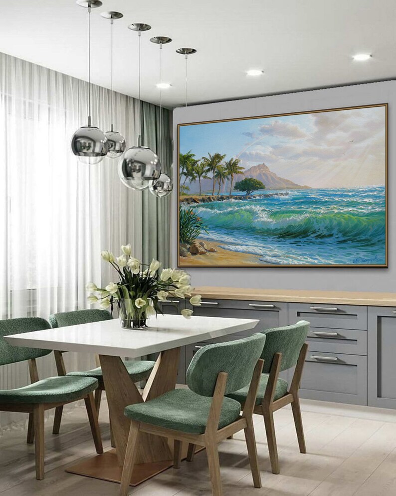 Puede incluir: Una mesa de comedor blanca con una base de madera y cuatro sillas verdes. Un cuadro grande de una escena de playa tropical con palmeras y olas cuelga de la pared detr&aacute;s de la mesa.