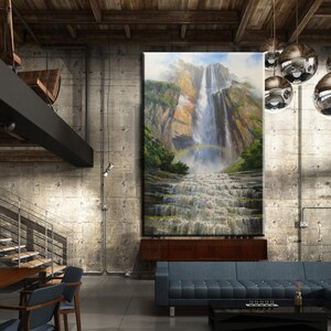 May include: A large, framed painting of a waterfall in a lush green forest hangs on a concrete wall in a modern loft living room. The room features a large sectional sofa, a wooden coffee table, and a dining table with chairs. The room has a rustic industrial design with exposed beams and pipes.