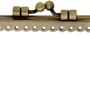 May include: An antique brass-toned purse frame with a scalloped edge and a decorative clasp. The frame has small holes for stitching and a classic, vintage aesthetic. The metal has a slightly aged appearance.