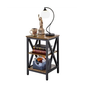 May include: A brown wooden end table with a black metal frame and three shelves. The table has a rustic look and is decorated with a lamp, a mug, and a statue of the Statue of Liberty.