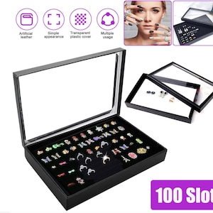 May include: Black ring storage box with a clear lid. The box has 100 slots for rings and is labeled "100 Slot".