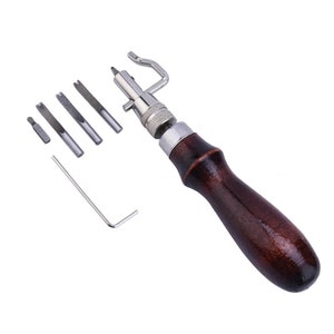 May include: A leather stitching tool with a wooden handle and a set of interchangeable needles. The tool is used for sewing leather and other materials.