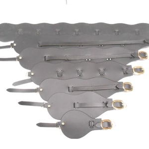 May include: A set of six black leather belts with gold buckles. The belts are of varying lengths and are arranged in a staggered pattern.