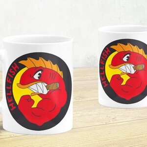 Peut inclure: Deux tasses en céramique blanche avec un motif de poisson de dessin animé rouge, jaune et noir. Le poisson fléchit son biceps et fume un cigare. Le texte "HELLFISH" est écrit verticalement sur la tasse.
