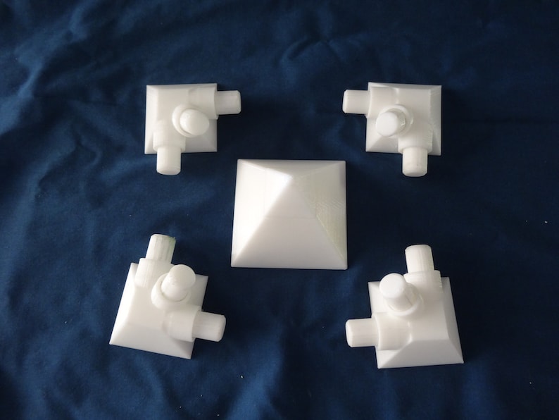 May include: Five white plastic corner pieces with a white pyramid in the centre. The corner pieces have three protruding knobs on each side.