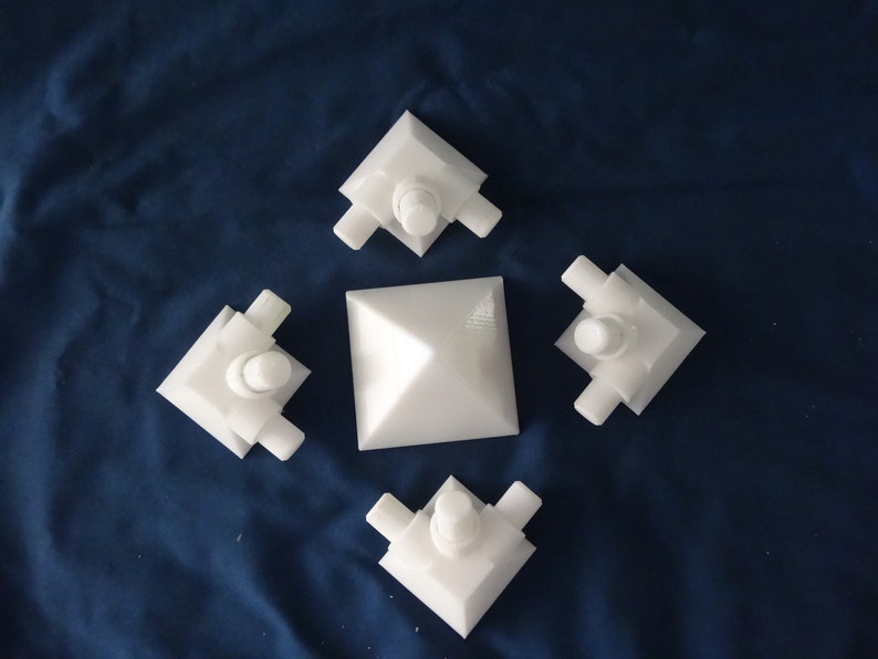 May include: Four white plastic corner pieces with a white pyramid in the centre. The corner pieces have a small round knob on top.