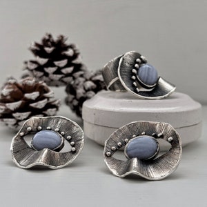 Puede incluir: Un conjunto de tres anillos de plata con piedras de &aacute;gata azul. Los anillos son de diferentes formas y tama&ntilde;os, y todos est&aacute;n engastados con una sola piedra de &aacute;gata azul. Los anillos son una pieza de joyer&iacute;a hermosa y &uacute;nica.