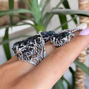 May include: A silver ring and earrings set with a black iridescent stone. The stone is set in a tree-like design.