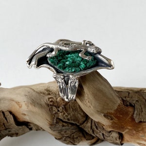 May include: A silver ring with a green malachite stone and a lizard design.