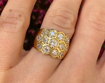 May include: A gold ring with a large, hexagonal-shaped cluster of small, clear diamonds.