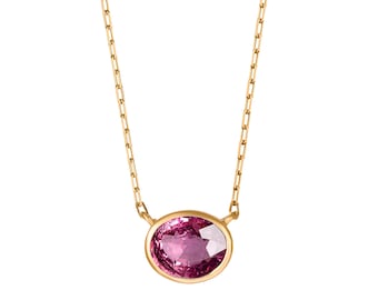 May include: A gold chain necklace featuring a single oval-shaped, faceted pink gemstone set in a smooth gold bezel. The delicate chain consists of small, elongated rectangular links that connect to the central pendant setting on both sides.