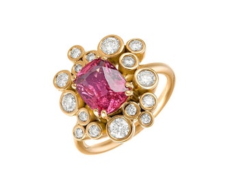 May include: A gold ring with a pink gemstone surrounded by smaller diamonds. The ring has a unique design with the diamonds set in a cluster around the center stone.