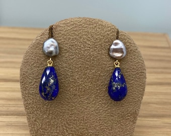 May include: A pair of gold earrings with a teardrop-shaped lapis lazuli stone and a baroque pearl on top.