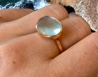 May include: A rose gold ring with a large oval-shaped clear gemstone.