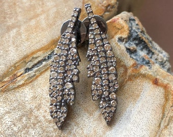 May include: A pair of silver feather earrings with small diamonds set in the metal. The earrings are a delicate and elegant design.