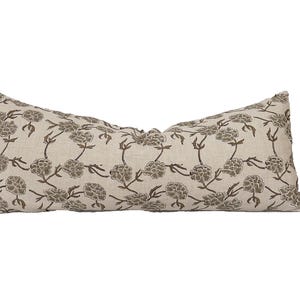 May include: A long, rectangular cushion with a beige linen fabric and a brown floral print. The cushion is filled with a soft, comfortable material.