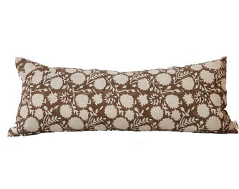 Puede incluir: Un cojín lumbar largo de color marrón y blanco con un diseño floral.