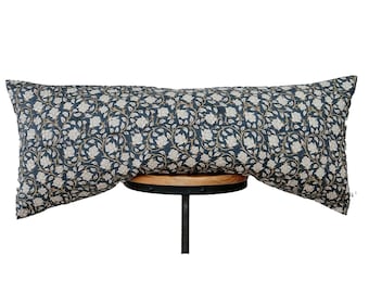 May include: A long, rectangular cushion with a dark blue background and a white floral pattern. The cushion is sitting on a wooden stool.