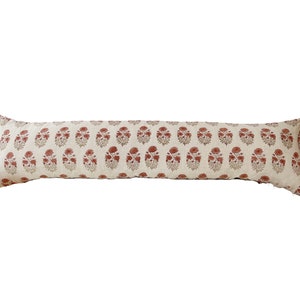 Könnte beinhalten: Ein langes, rechteckiges Kissen mit einem weißen Leinenbezug und einem sich wiederholenden Muster aus roten Blumenmotiven.