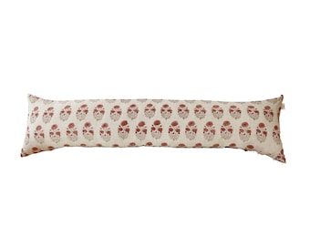 May include: A long, rectangular cushion with a white linen cover and a repeating pattern of red floral motifs.