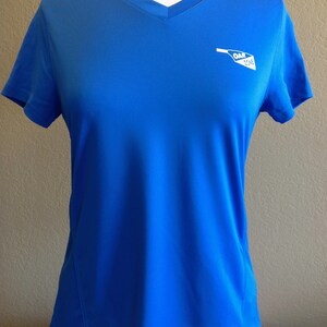 May include: A royal blue short-sleeved t-shirt with a white v-neck and a white logo that says "OAR ZONE" on the right side of the chest.