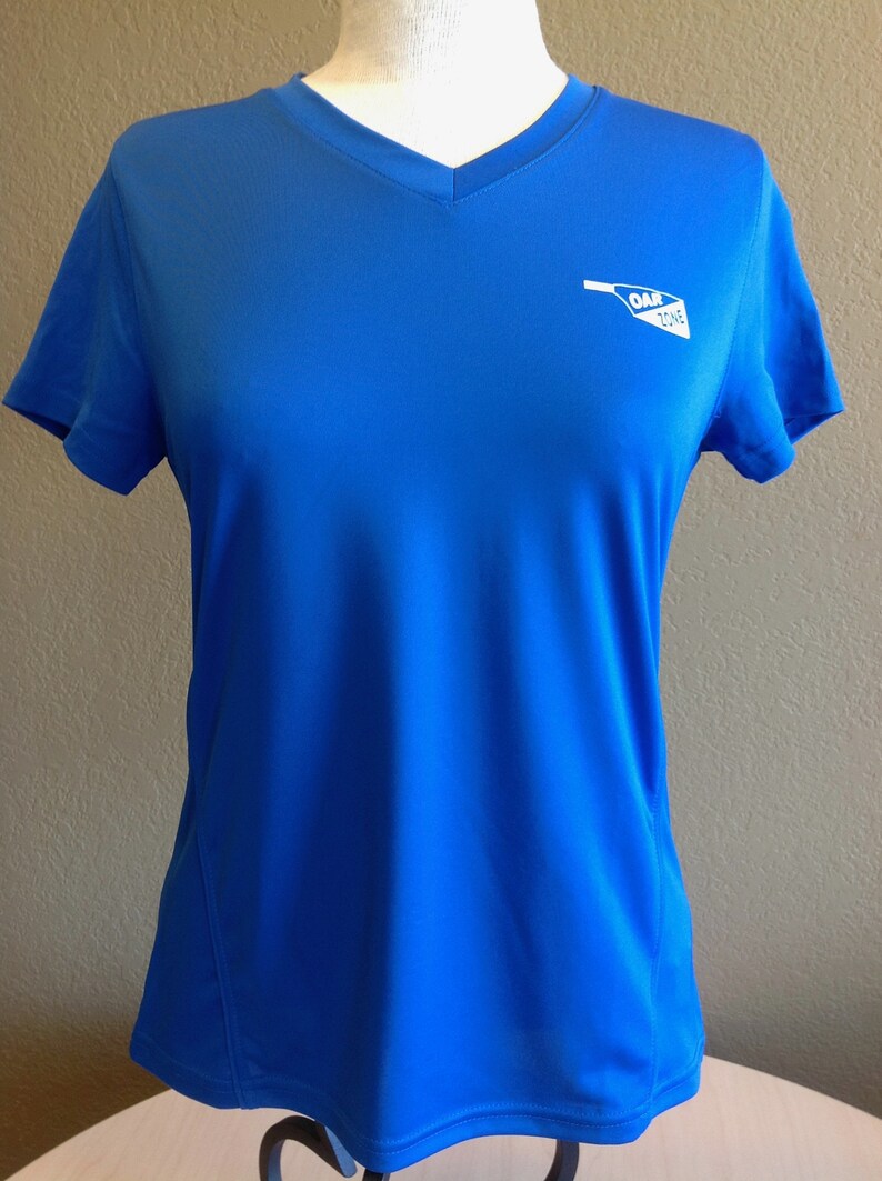 May include: A royal blue short-sleeved t-shirt with a white v-neck and a white logo that says "OAR ZONE" on the right side of the chest.
