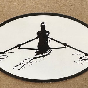 May include: Oval sticker featuring a black and white illustration of a rower in a boat. The rower is silhouetted, holding oars, with water lines depicted below. The sticker has a black border.