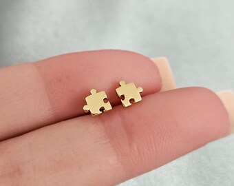 May include: A pair of gold-toned puzzle piece stud earrings. The earrings are small and delicate, and they are perfect for everyday wear.