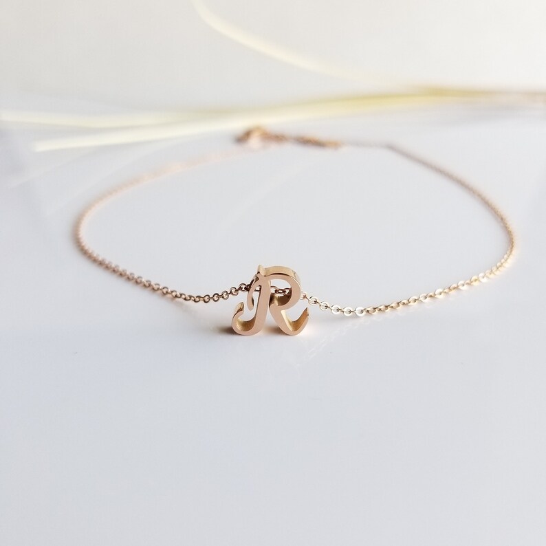 May include: A gold-toned necklace with a cursive letter 'R' pendant.
