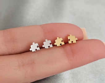 May include: Three pairs of puzzle piece earrings in silver, gold, and rose gold.