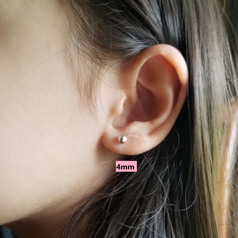 May include: Close-up of a person's ear with a small silver stud earring. The earring is 4mm in diameter.