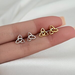 May include: A pair of small, simple earrings with a Celtic knot design. One pair is gold and the other is silver.