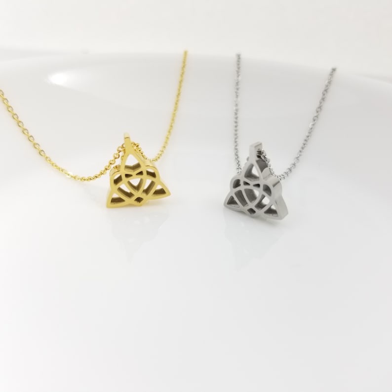 May include: Two delicate necklaces with a Celtic knot pendant. One necklace is gold and the other is silver.