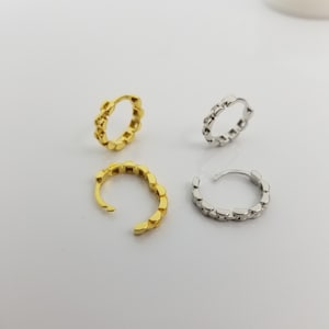 May include: Four hoop earrings, two gold and two silver, with a chain-link design.