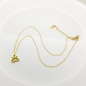 May include: A gold-toned necklace with a Celtic knot pendant. The chain is a delicate, thin chain.