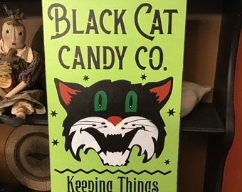 May include: A rectangular sign with a bright green background features the text "BLACK CAT CANDY CO." and a black cat graphic. The sign also reads "Keeping Things Purrfectly Sweet" and lists candy types. The sign is dated "SINCE 1876."