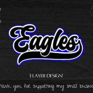 May include: A black and white design of the word "Eagles" in a bold, cursive font with a blue outline. The text is on a dark wood background. The text "3 LAYER DESIGN!" is below the word "Eagles".