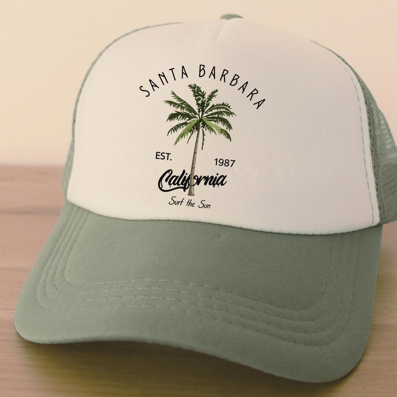 Pu&ograve; includere: Cappellino da camionista bianco e verde con la scritta "Santa Barbara" e una grafica di palma. Il cappellino presenta anche la scritta "California" e "Surf the Sun". Il cappellino ha una visiera curva e un retro in rete.