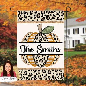 May include: A white garden flag with a leopard print design. The flag features a pumpkin with gold glitter accents and the text "The Smiths".