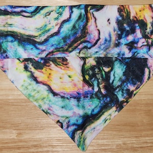 May include: A triangular bandana with a colorful abstract pattern resembling a swirling, marbled design in shades of blue, green, yellow, pink, and black.