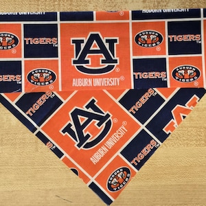 May include: A blue and orange fabric dog bandana with the Auburn University logo and the words "Tigers" repeated throughout the design.